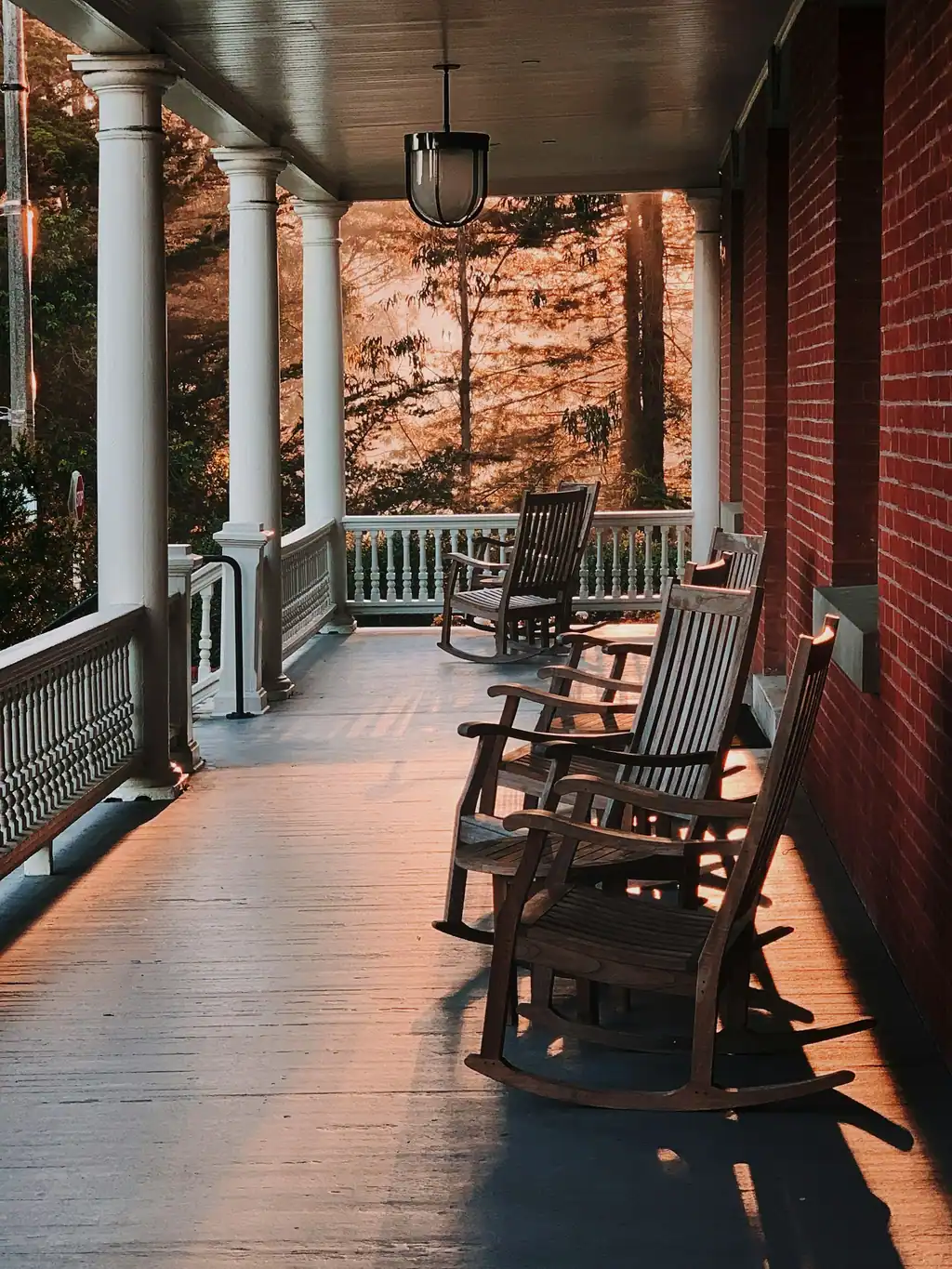 A covered front porch with wood rocking chairs and white columns