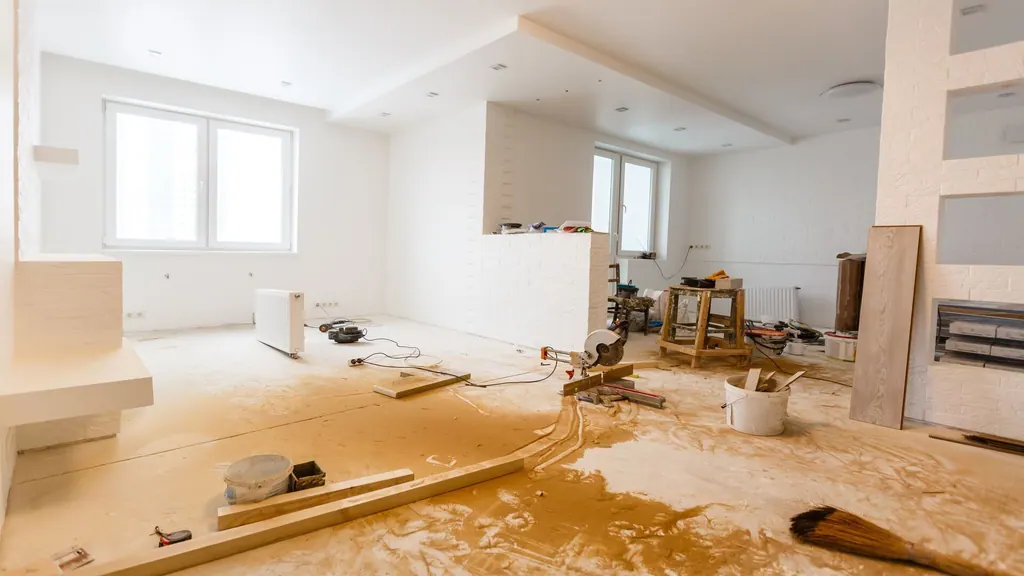 A white room mid-renovation with flooring materials and tools on the floor