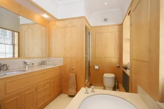 A bathroom with a wood vanity, wood-panelled walls and a tub