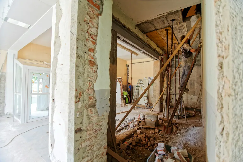 A house mid-remodel: one room finished and bright, the next still open to brick and framing